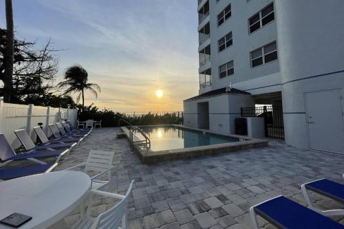 a patio with chairs and a pool and a building at Estero Island Beach Villas 105 in Fort Myers Beach