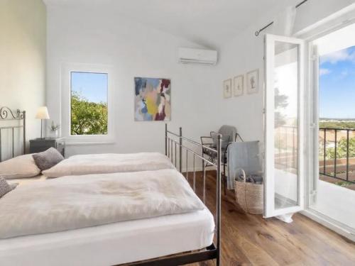 a white bedroom with two beds and a balcony at El Dorado in Premantura