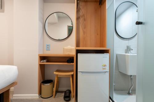 a small bathroom with a white refrigerator and a sink at KIMSTEL Jongno in Seoul