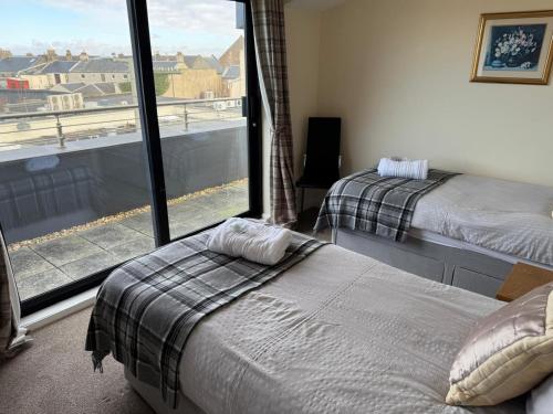 a bedroom with two beds and a large window at The Penthouse- The Kingsley Collection in Troon