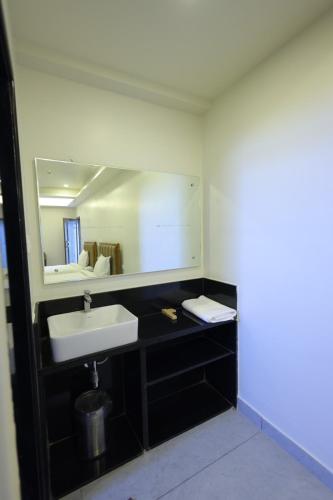 a bathroom with a sink and a mirror at Hotel Rock Port Inn in Rushikonda
