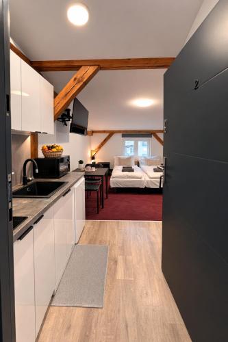 a kitchen and living room with a bed in the background at Apartamenty Stary Młyn in Wronki