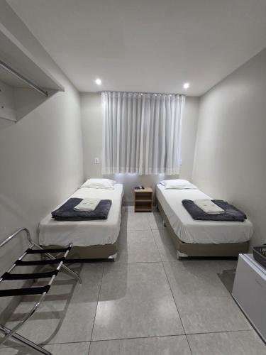 ein Schlafzimmer mit zwei Betten und einem Fenster in der Unterkunft HOTEL POLASTRELLI in Governador Valadares