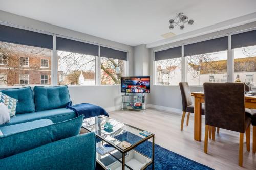 a living room with a blue couch and a table at Seafarers - Contemporary Apartment, Central Location in Poole