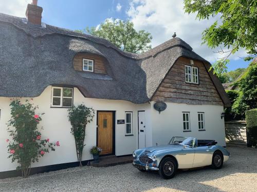 a car parked in front of a thatched house at Riverside Lodge Pied a Terre in Fordingbridge