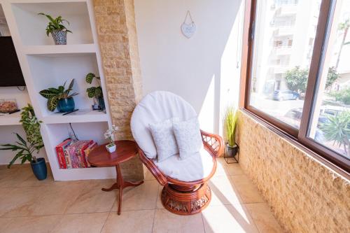 a room with a chair and a window at Piale Palms Makenzie Beach Front Apartment Larnaca Airport Area in Larnaca