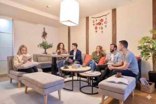 a group of people sitting in a waiting room at Kizuna 絆 - 5 Bedding in 2 Japanese-style Bed Rooms, 11 PAX, 30min to USJ, Kaiyukan Aquarium, Namba, Osaka Catsle, and Tsutenkaku Tower, Self-check-in Property, Quiet Neighborhood Stay, Perfect for Families & Business Guests, Extended Stay Perks in Osaka