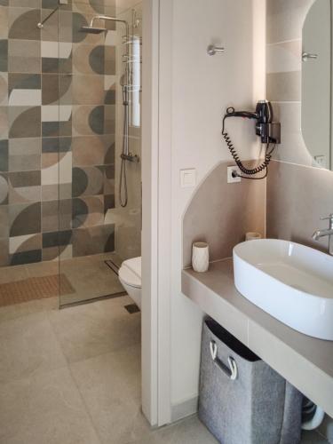 a bathroom with a sink and a toilet and a shower at Abelia Abode Apt in Kavros