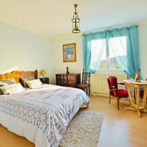 a bedroom with a bed and a table and a window at La maison de Dourils in Entraygues-sur-Truyère