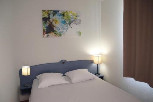 a bedroom with a bed with two pillows and a painting at Oly Vacances Les Landes in Cassen