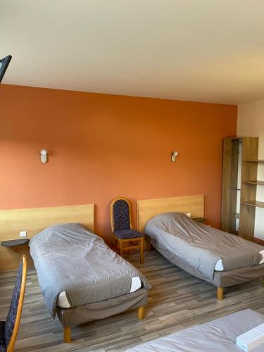 two beds in a room with orange walls at Le Trianon in Hesdin