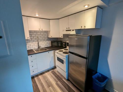 a kitchen with white cabinets and a stainless steel refrigerator at Les appartements HOMA in Montréal