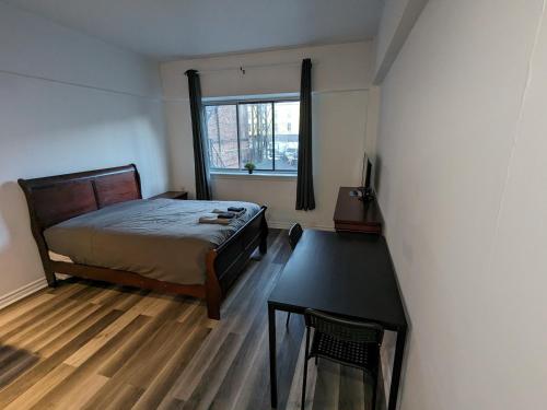 a bedroom with a bed and a table and a window at Les appartements HOMA in Montréal
