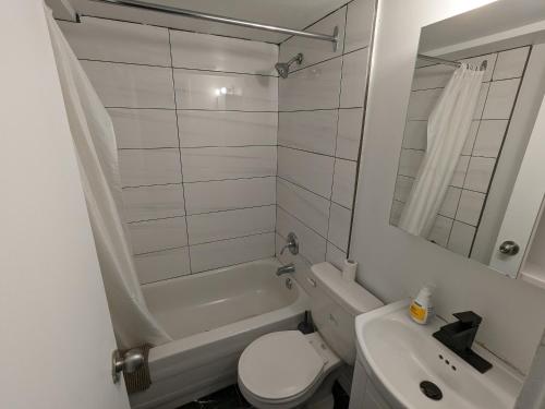 a white bathroom with a toilet and a sink at Les appartements HOMA in Montréal