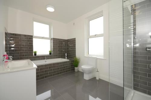 a bathroom with a tub and a toilet and a sink at York Boutique House- spacious & stylish with free parking in York