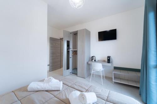 a white bedroom with a bed and a desk at Via del Mare in Giba
