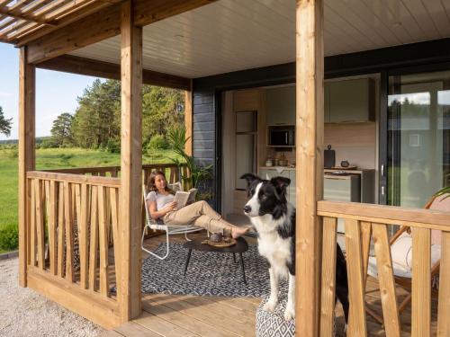 a woman sitting on the porch of a house with a dog at Camping Castelló Mar in Empuriabrava