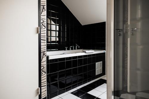 a bathroom with a sink and a black tiled wall at Jehan De Beauce - Teritoria in Chartres