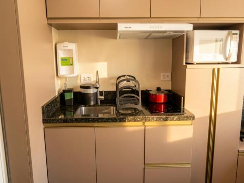 a small kitchen with a sink and a counter top at Campos Sales by Xtay - Studios completos na região judiciária de Juvevê in Curitiba