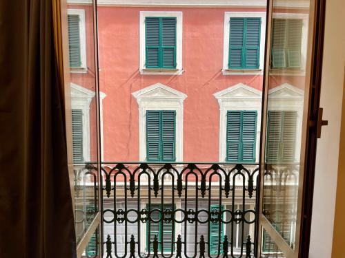 a window with a view of a building with green shutters at RELSTAY - Assarotti Suites in Genoa