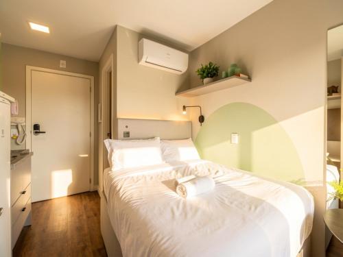 a bedroom with a large bed with white sheets at Campos Sales by Xtay - Studios completos na região judiciária de Juvevê in Curitiba
