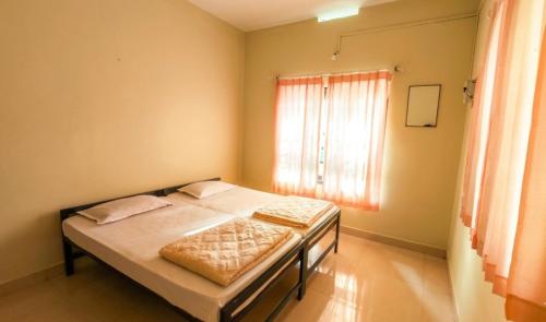 a bedroom with a bed with two pillows and a window at Villa 9 degrees north in Sultan Bathery