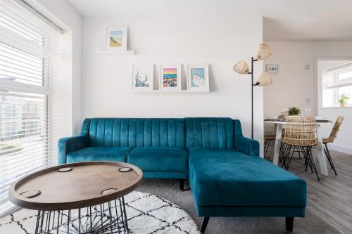 a living room with a blue couch and a table at Seas the Day - Moments from Hamworthy Beach and Park in Poole