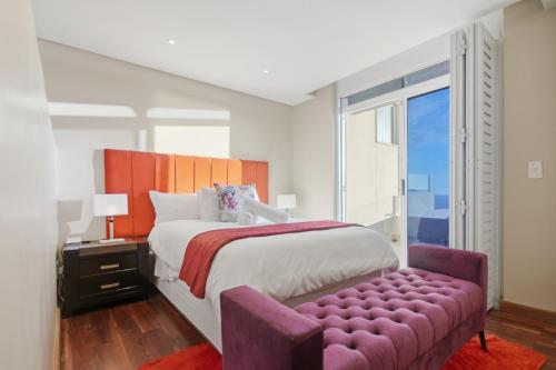 a bedroom with a large bed with a purple ottoman at White Waters in Cape Town