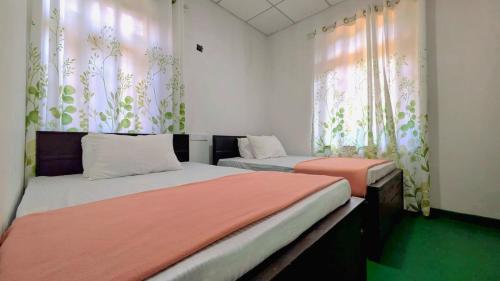 two beds in a room with curtains and avertisementvertisement at Haputale Hills Holiday Home in Haputale