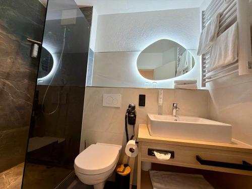 a bathroom with a sink and a toilet and a mirror at Seespitz Gästehaus in Herrsching am Ammersee