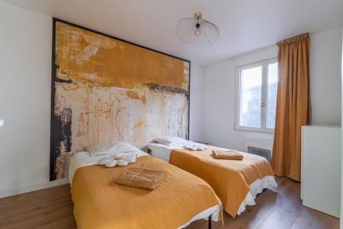 two beds in a room with a painting on the wall at Appartement devant Nausicaa in Boulogne-sur-Mer