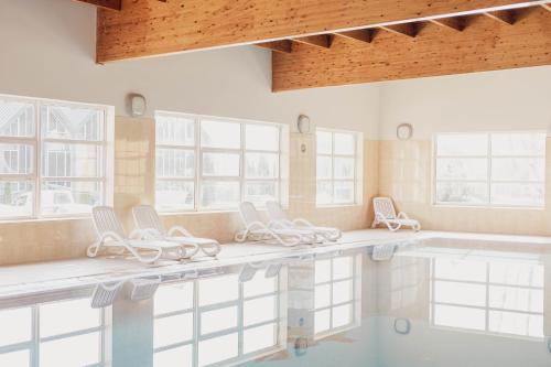 a swimming pool with white chairs and a swimming pool at Kamienica Parkowa in Dąbki