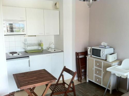 Il comprend une petite cuisine avec une table, des chaises et un four micro-ondes. dans l'établissement NICE FLAT 400 m FROM BEACH & CENTER, à Cabourg