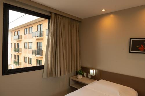 a bedroom with a bed and a window with a building at Imperial Hotel in Imperatriz