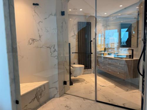 a bathroom with a glass shower and a toilet at سكاي لاين سويت in Tunis
