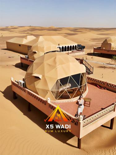 a man standing in front of a boat in the desert at X5 wadi Rum Luxury in Wadi Rum