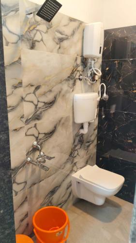 a bathroom with a white toilet and a marble wall at Rmeshwar homestay in Malvan