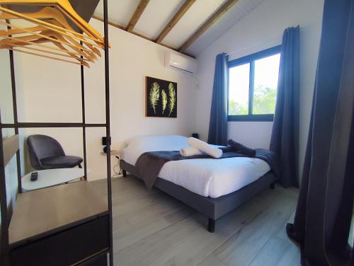 a bedroom with a bed and a chair and a window at Swisstropiclodges avec piscine privée in Sainte-Anne