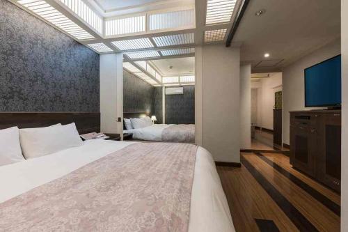 a bedroom with a large bed and a flat screen tv at ホテルロアール 大人専用 in Miyake
