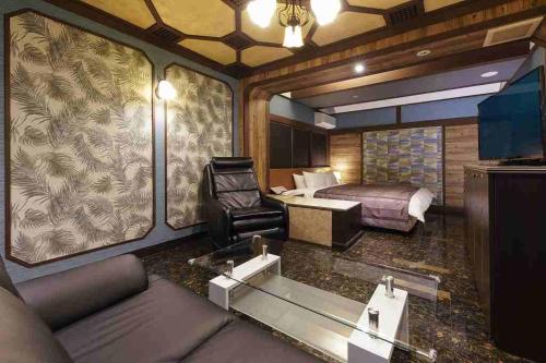 a room with a bed and a couch and a desk at ホテルロアール 大人専用 in Miyake