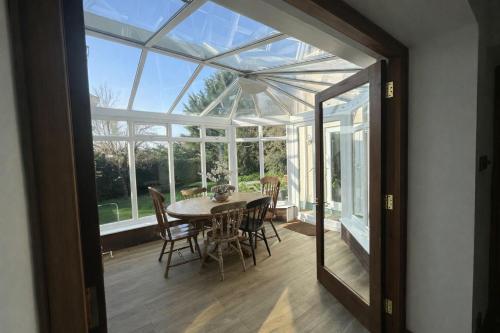 a glass conservatory with a table and chairs at Lamack Vale House, Tenby, 5 Bedrooms with Private Heated Indoor Swimming Pool & Parking in Tenby