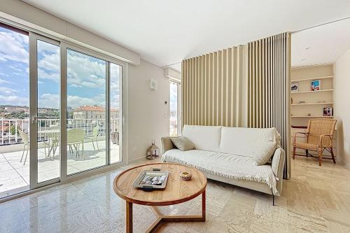 a living room with a couch and a table at Sea View Terrace Penthouse Garage Walk to the Palais in Cannes