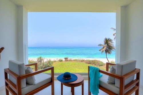 a room with a view of the ocean from a balcony at Diamonds Leisure Beach & Golf Resort in Diani Beach