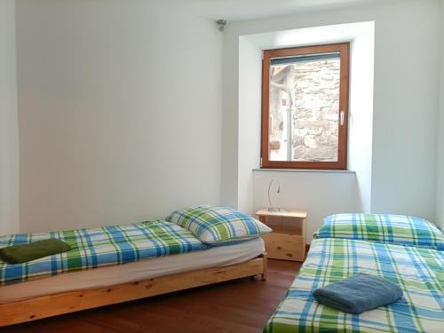zwei Betten in einem Zimmer mit Fenster in der Unterkunft Appartement "Luigi Loft" in Intragna