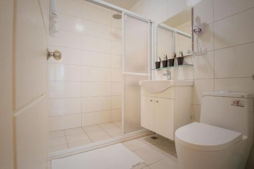 a white bathroom with a toilet and a shower at Alan's House B&B in Jiaoxi
