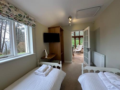 two beds in a room with two windows and a television at Cottage No1 Four Bed Lakeland Retreat and Hot Tub in Elterwater
