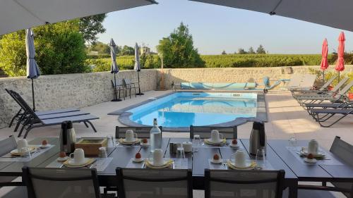 a patio with a table and chairs and a swimming pool at Au clocher in Saint-Seurin-de-Cadourne