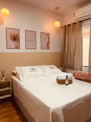 a bedroom with a bed with white sheets and a window at Casa Pires - Sinop MT in Sinop
