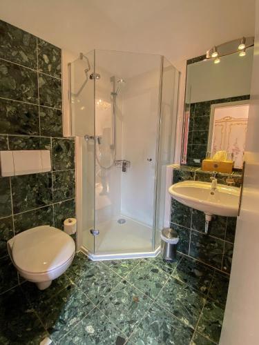 a bathroom with a shower and a toilet and a sink at Hotel Stadtherz in Burgwedel