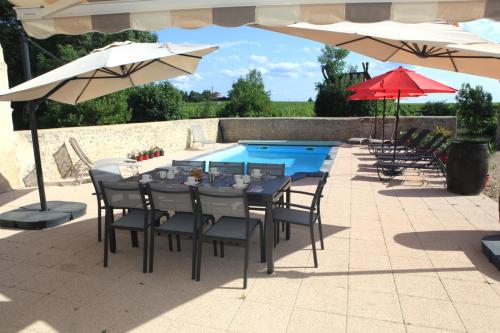 a table with chairs and umbrellas next to a pool at Au clocher in Saint-Seurin-de-Cadourne